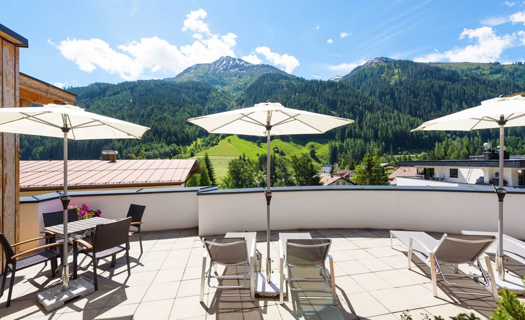 Große Sonnenterrasse mit Liegestühlen und Bergblick in den Apartments am Arlberg.